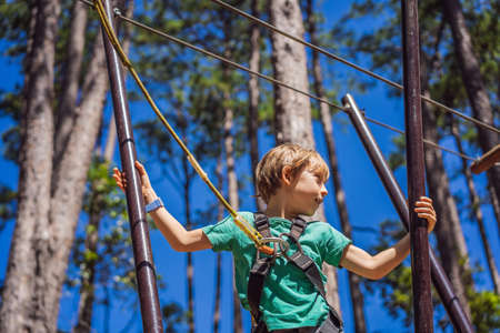 Portrait of cute little boy walk on a rope bridge in an adventure rope park.の写真素材