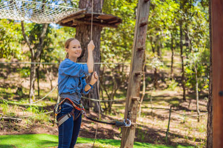 Young attractive woman in adventure rope park in safety equipment
