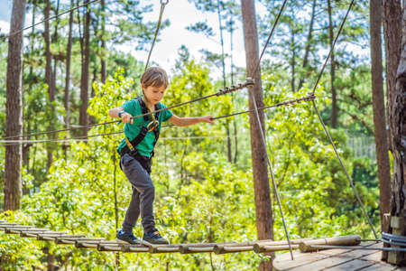 Portrait of cute little boy walk on a rope bridge in an adventure rope parkの写真素材