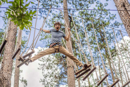 Young attractive man in adventure rope park in safety equipmentの写真素材