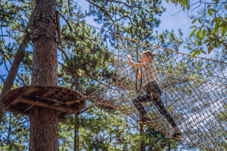 Young attractive woman in adventure rope park in safety equipment