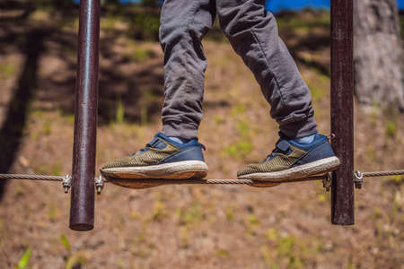 Portrait of cute little boy walk on a rope bridge in an adventure rope parkの写真素材