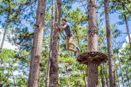 Young attractive man in adventure rope park in safety equipmentの写真素材