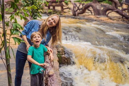 Mom and son on the background of Majestic landscape of waterfall in summer at Dalat, Vietnamの写真素材
