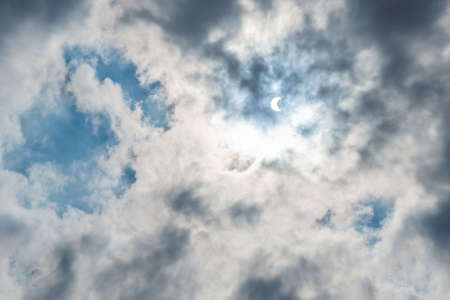 Solar Eclipse in blue sky among the clouds.