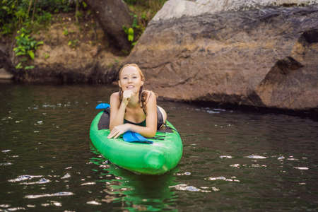 Side view picture of a woman sitting and relaxing on the sup board. Surfer woman resting