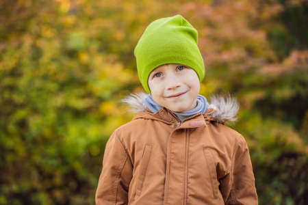 Portrait of little smiling child on head background of sunny autumn parkの写真素材