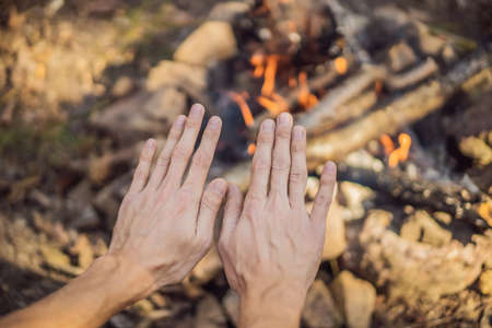 man warming his hands by a fire. Poor men warm outdoors near smoking barreの写真素材