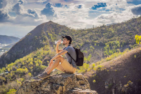 A young man local tourist sits on a rock and enjoys the view of her city. Local tourism concept....