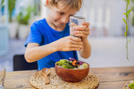 Boy eating Poke bowl with shrimp, corn, avocado, ginger and mushrooms