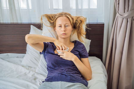 Extremly tired young woman lying on the bed, home alone. self-isolation at home, quarantine due to...