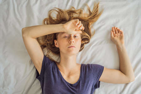 Extremly tired young woman lying on the bed, home alone. self-isolation at home, quarantine due to pandemic COVID 19. Mental health problems in self-isolation at homeの写真素材