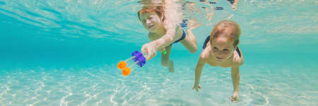 Cute boys swimming underwater in shallow turquoise water at tropical beach BANNER, LONG FORMAT