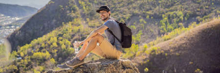 A young man local tourist sits on a rock and enjoys the view of her city. Local tourism concept....