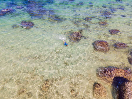 Boy is snorkeling among the corals. View from the droneの写真素材