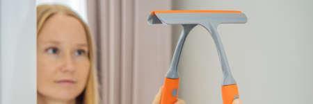 Young beautiful woman cleaning mirror. Cleaning service. Maid cleaning at home BANNER, LONG FORMAT