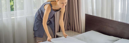 Young Female Housekeeper Changing Bedding In Hotel Room BANNER, LONG FORMAT