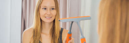 Young beautiful woman cleaning mirror. Cleaning service. Maid cleaning at home BANNER, LONG FORMAT