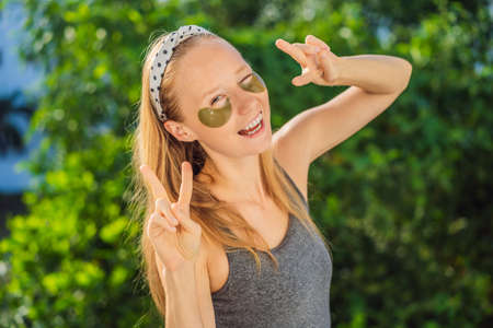 Smiling woman applying hydrogel eye care patches, moisturizing skin under eyes, enjoying skincare...