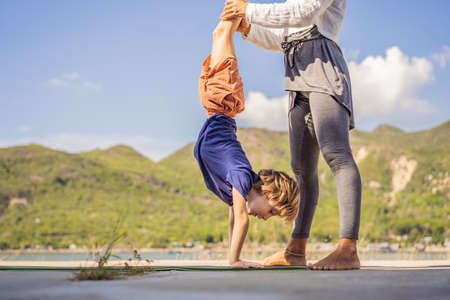 Boy doing yoga on a yoga mat against a background of mountainsの写真素材