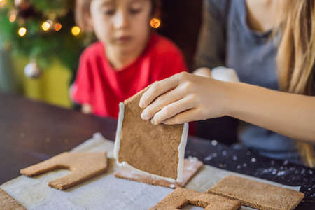 Young mother and kid making gingerbread house on Christmas eveの写真素材
