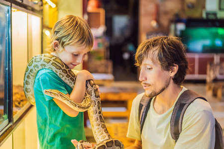 Smiling boy and his father holding python in hands