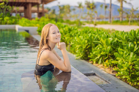 Woman relaxing in infinity swimming pool looking at view