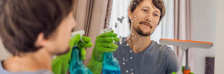 Young man cleaning mirror at home hotel BANNER, LONG FORMAT