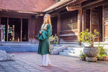 Woman tourist in national vietnamese dress in Temple of Literature in Hanoi in Southeast Asia,...