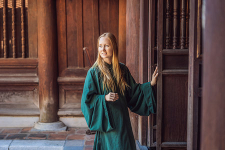 Woman tourist in national vietnamese dress in Temple of Literature in Hanoi in Southeast Asia,...