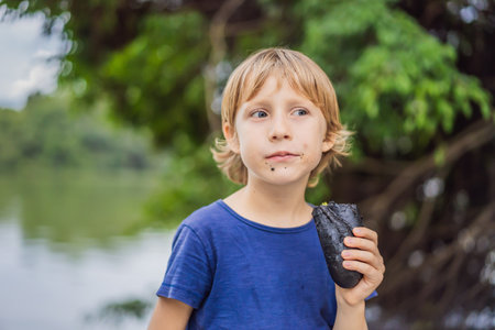Boy eating Vietnamese Pork Banh Mi Sandwich in a black baguette
