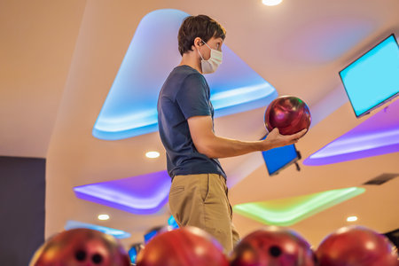 Man playing bowling with medical masks during COVID-19 coronavirus in bowling clubの写真素材