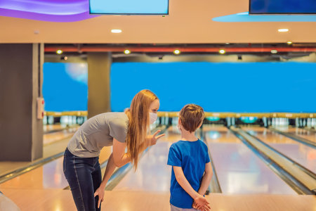 beautiful young mother and son playing bowling with medical masks during COVID-19 coronavirus in bowling clubの写真素材