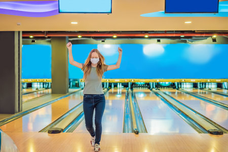 Woman playing bowling with medical masks during COVID-19 coronavirus in bowling clubの写真素材
