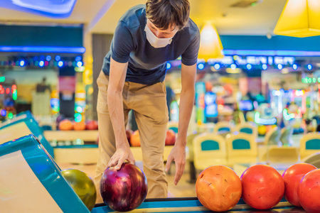 Man playing bowling with medical masks during COVID-19 coronavirus in bowling clubの写真素材
