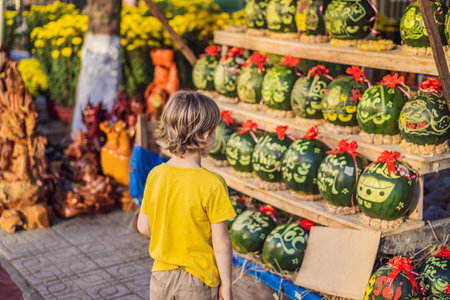 Boy tourist look at Watermelons with festive engraving on Tet Eve. Tet is Lunar New Year and celebrated during four days in Vietnamの写真素材