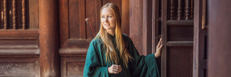 BANNER, LONG FORMAT Woman tourist in national vietnamese dress in Temple of Literature in Hanoi in...