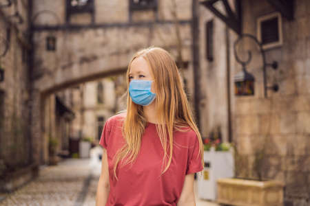 Young woman wearing a medical mask during pandemic tourist walks down the street in a European city after the end of quarantineの写真素材