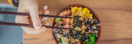 Woman eating Raw Organic Poke Bowl with Rice and Veggies close-up on the table. Top view from above horizontal BANNER, LONG FORMATの写真素材