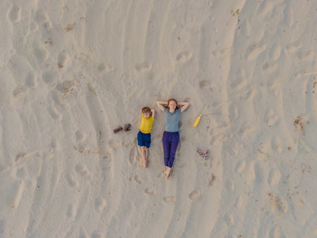 Mom and son are lying on the sand at sunset. View from the drone. Paradise, travel, vacation conceptの写真素材