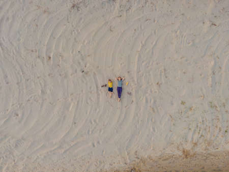 Mom and son are lying on the sand at sunset. View from the drone. Paradise, travel, vacation conceptの写真素材