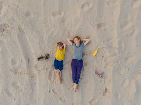 Mom and son are lying on the sand at sunset. View from the drone. Paradise, travel, vacation conceptの写真素材