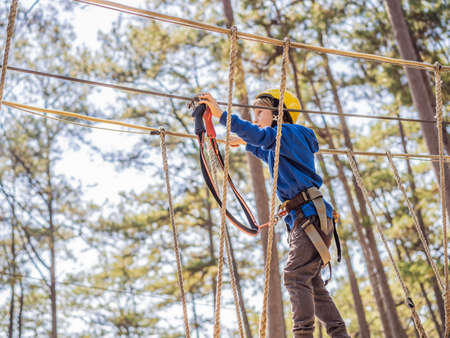 Happy child in a helmet, healthy teenager school boy enjoying activity in a climbing adventure park on a summer dayの写真素材
