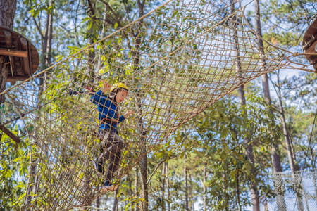 Happy child in a helmet, healthy teenager school boy enjoying activity in a climbing adventure park on a summer dayの写真素材