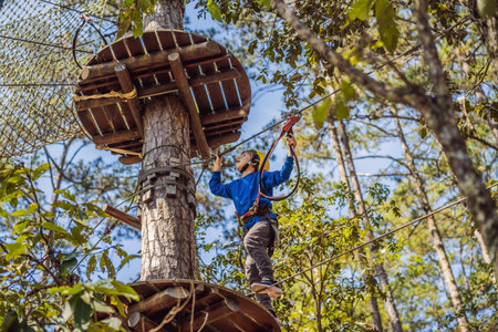 Happy child in a helmet, healthy teenager school boy enjoying activity in a climbing adventure park...