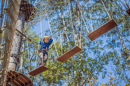 Happy child in a helmet, healthy teenager school boy enjoying activity in a climbing adventure park on a summer dayの写真素材