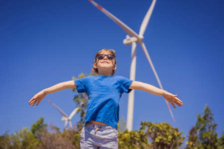 Alternative energy, wind farm and happy time with your family. Happy boy on vacation and escape to natureの写真素材