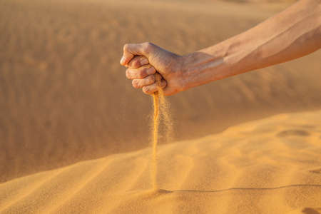 Desert, sand puffs through the fingers of a mans handの写真素材