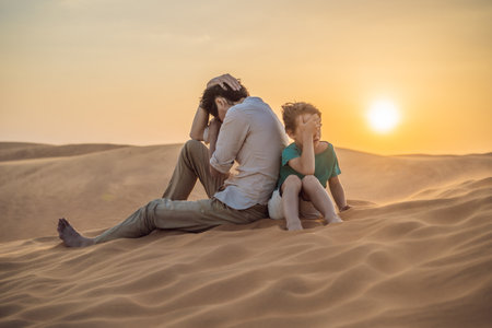 Relationship problems between father and son. Family conflict. Dad and son have a heated relationship, sit in the hot desert with their backs to each other and do not want to talkの写真素材