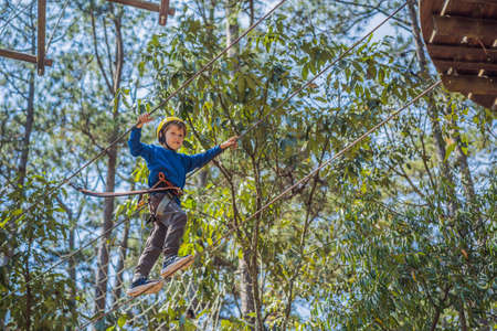 Happy child in a helmet, healthy teenager school boy enjoying activity in a climbing adventure park on a summer dayの写真素材